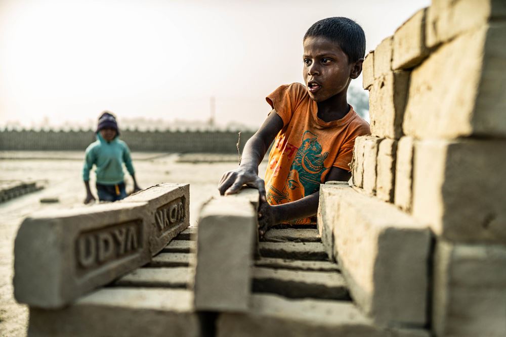 Junge in der Ziegelei stapelt Ziegel Foto : Jakob Studnar / Kindernothilfe. Junge in der Ziegelei stapelt Ziegel Foto : Jakob Studnar / Kindernothilfe.