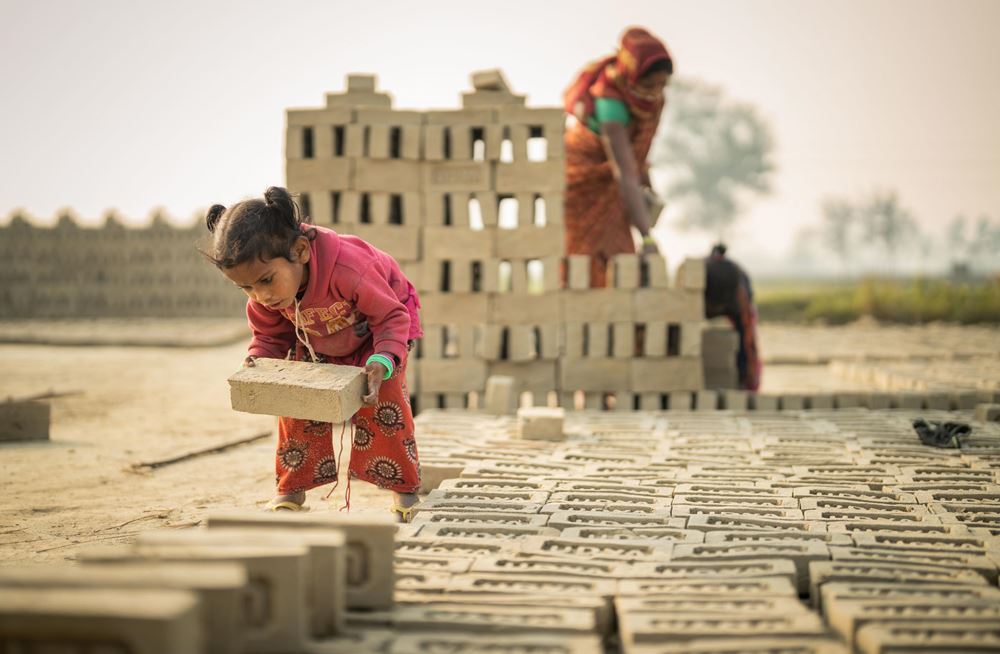 Mädchen trägt schweren Ziegel (Quelle: Jakob Studnar) Mädchen trägt schweren Ziegel (Quelle: Jakob Studnar)