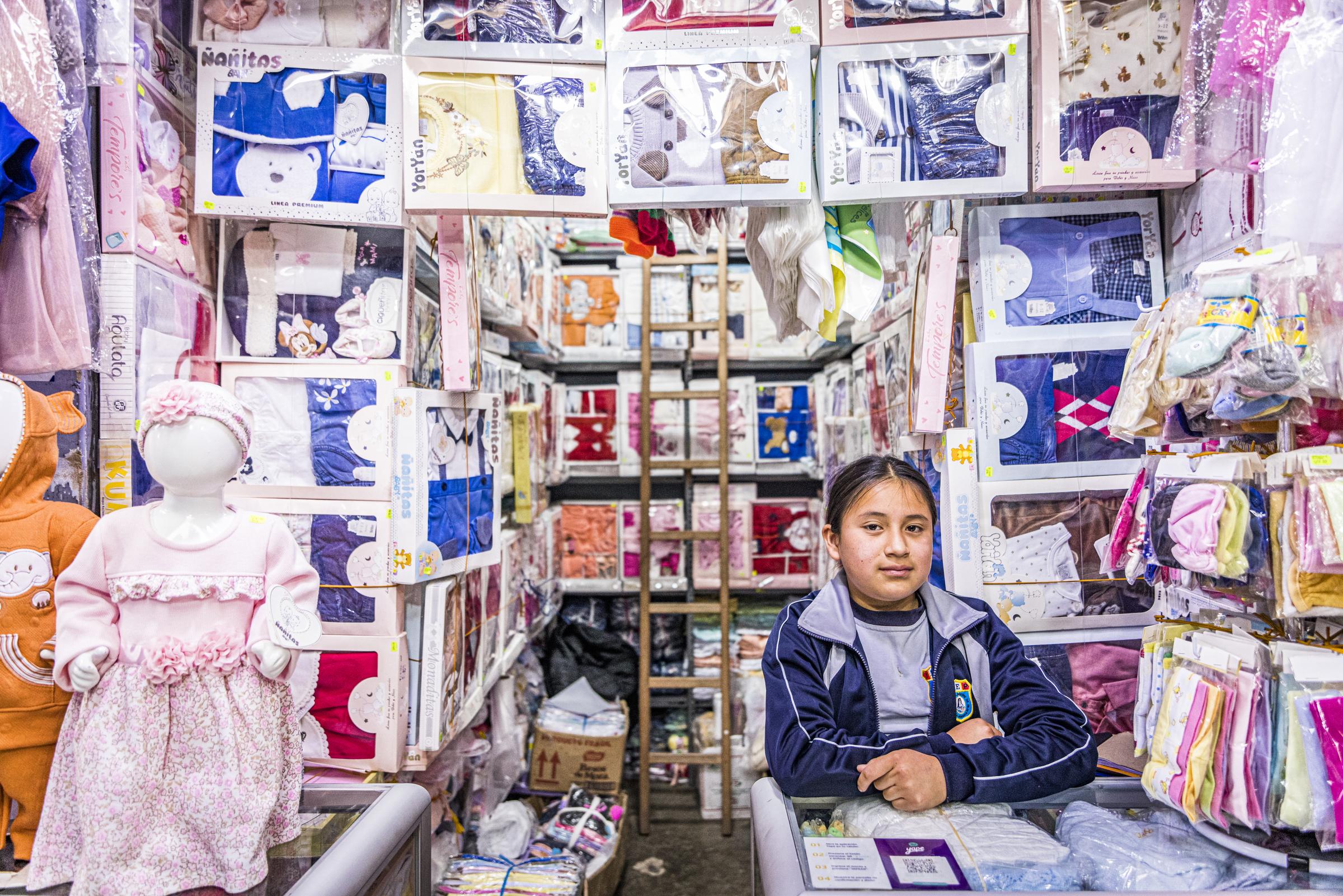 Junges Mädchen sitzt an Ladentheke eines Klamottengeschäfts (Quelle: Kindernothilfe)