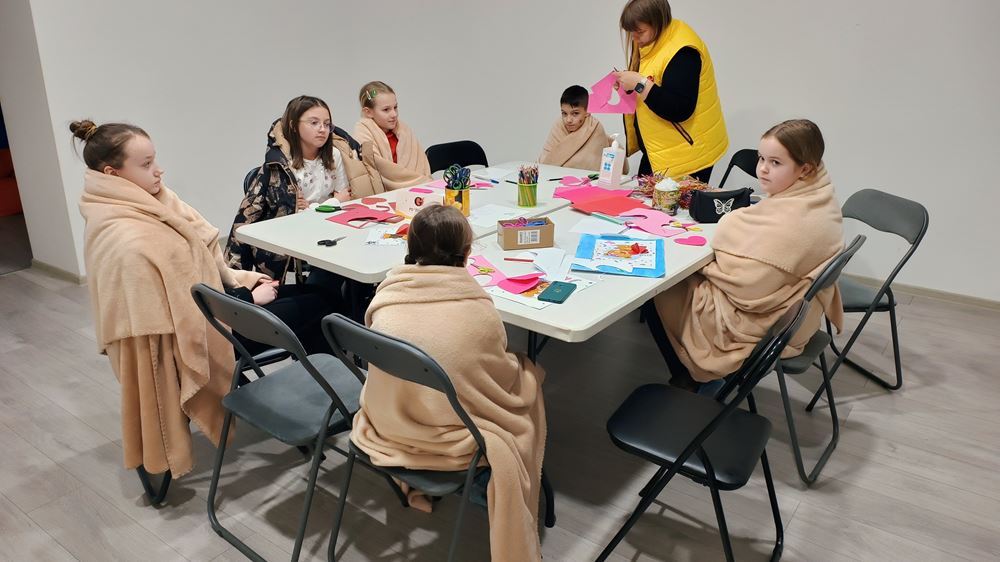 Kinder sitzen in Decken gehüllt am Tisch (Quelle: NGO Girls)